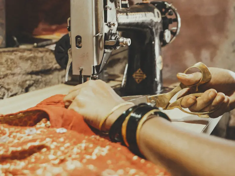 Hands cutting embroidered fabric with scissors