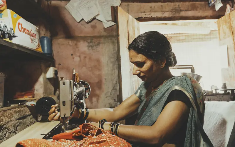 A woman stitching on a sewing machine in her home workshop